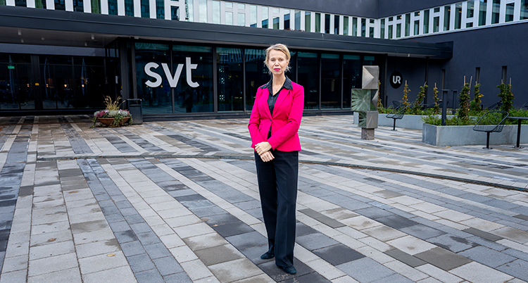 Hon står utanför SVTs hus i rosa kavaj.