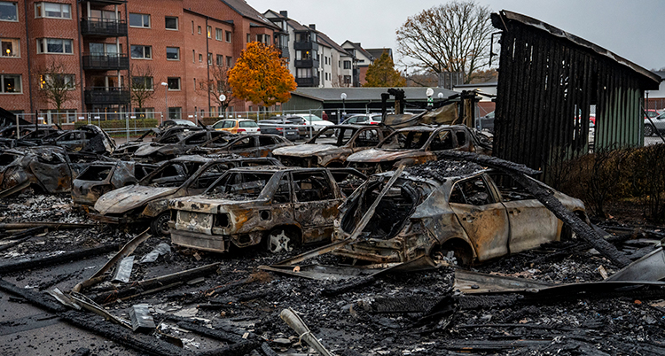 Många bilar som brunnit på en parkeringsplats.