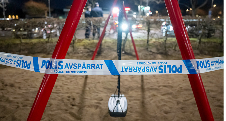 Det är mörkt. Poliserna har spärrat av vid en lekplats.