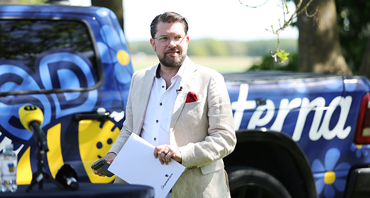 Jimmie Åkesson står utomhus och har en träff för journalister.