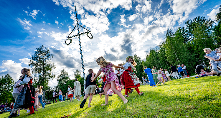 Barn leker runt en midsommarstång.