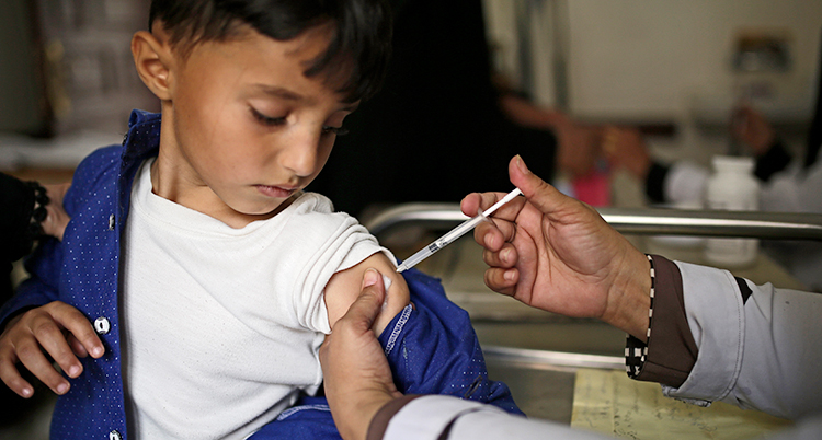 En liten pojke får en spruta med vaccin i armen.