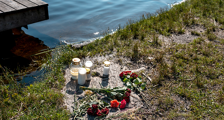 Blommor och ljuslyktor på stranden vid en sjö.
