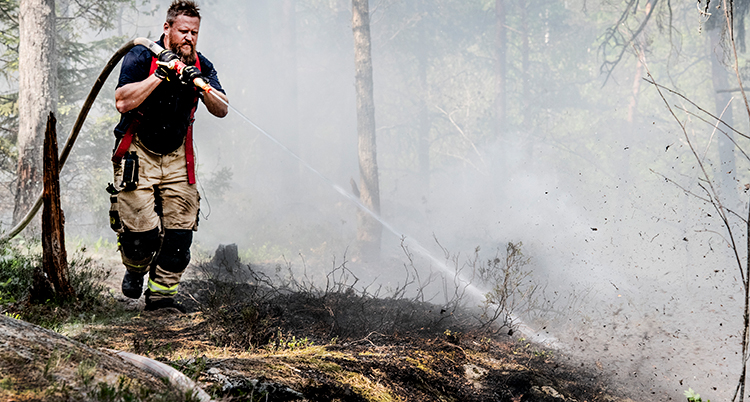 En brandman släcker en brand på marken.