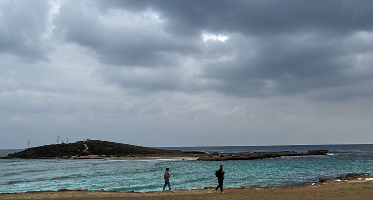 Två personer går på en strand.