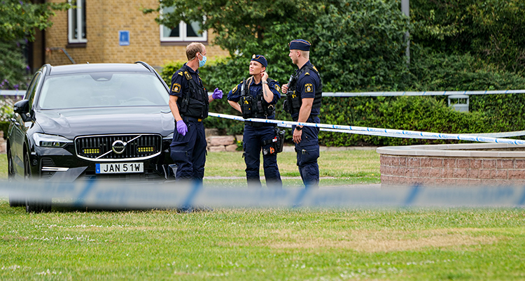 Poliser och avspärrande band vid en gräsmatta.